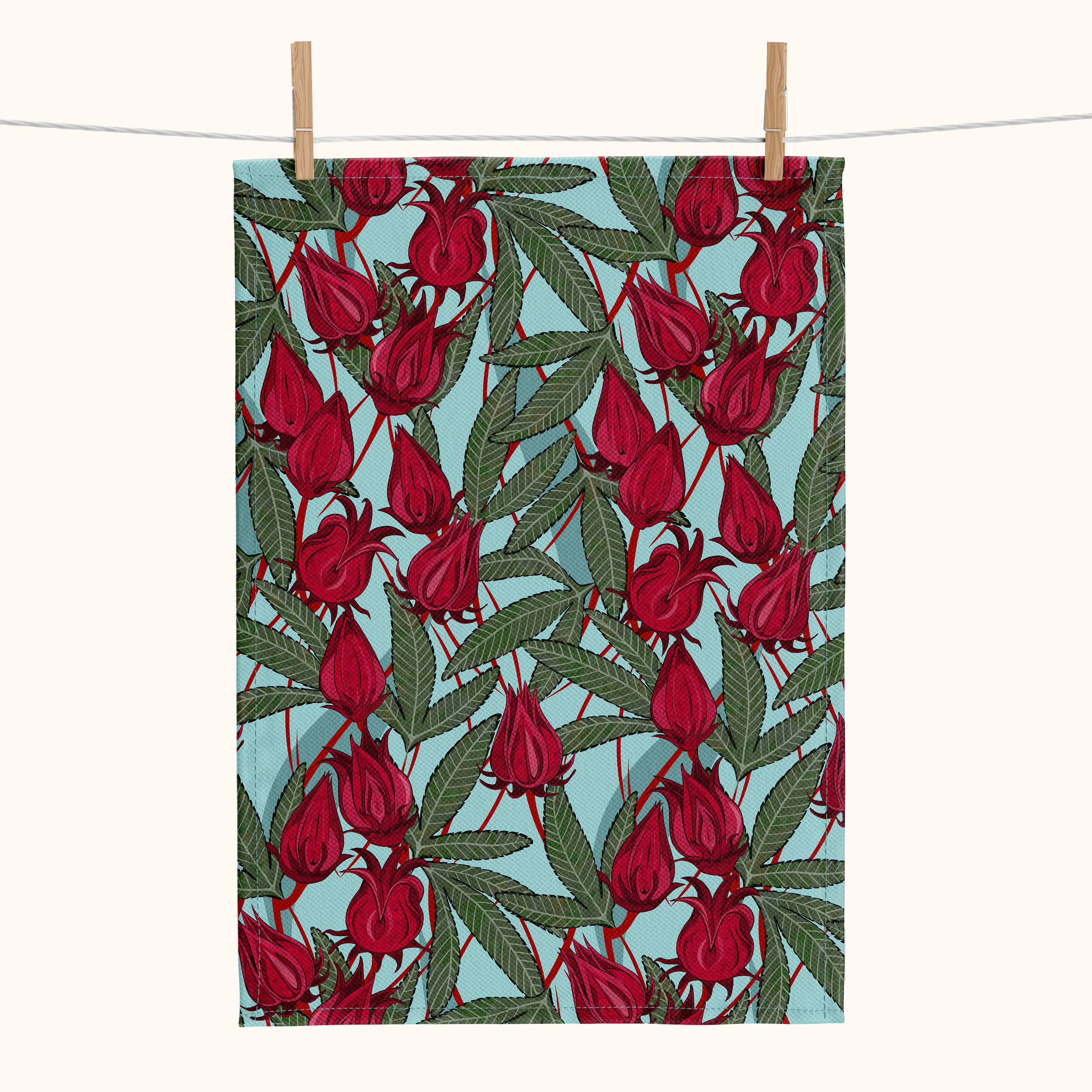 Linen tea towel with pattern of rosella blossoms and leaves on a pale blue background