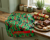 linen tea towel featuring an all-over bottlebrush design draped on a bench with Christmas crackers and food