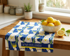 linen tea towel featuring a stylised all-over sulphur-crested cockatoo design with a blue background on a bench with a bowl of lemons