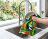 a dish being dried with a linen tea towel with a bright pattern showing Torres Strait pigeons and fruiting carpenteria palm 