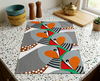 linen tea towel printed with large stylised zebra finches on a green background lying flat on a kitchen bench